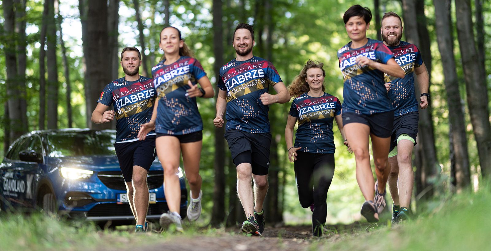 Sechs Läufer auf einem Waldweg in einheitlichen Shirts des Kanclerz-Halbmarathons Zabrze