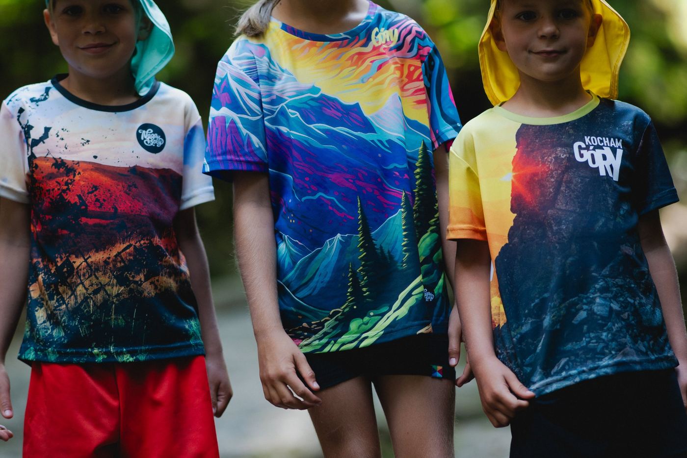 Drei Kinder in bunten Sportshirts mit Bergmotiv